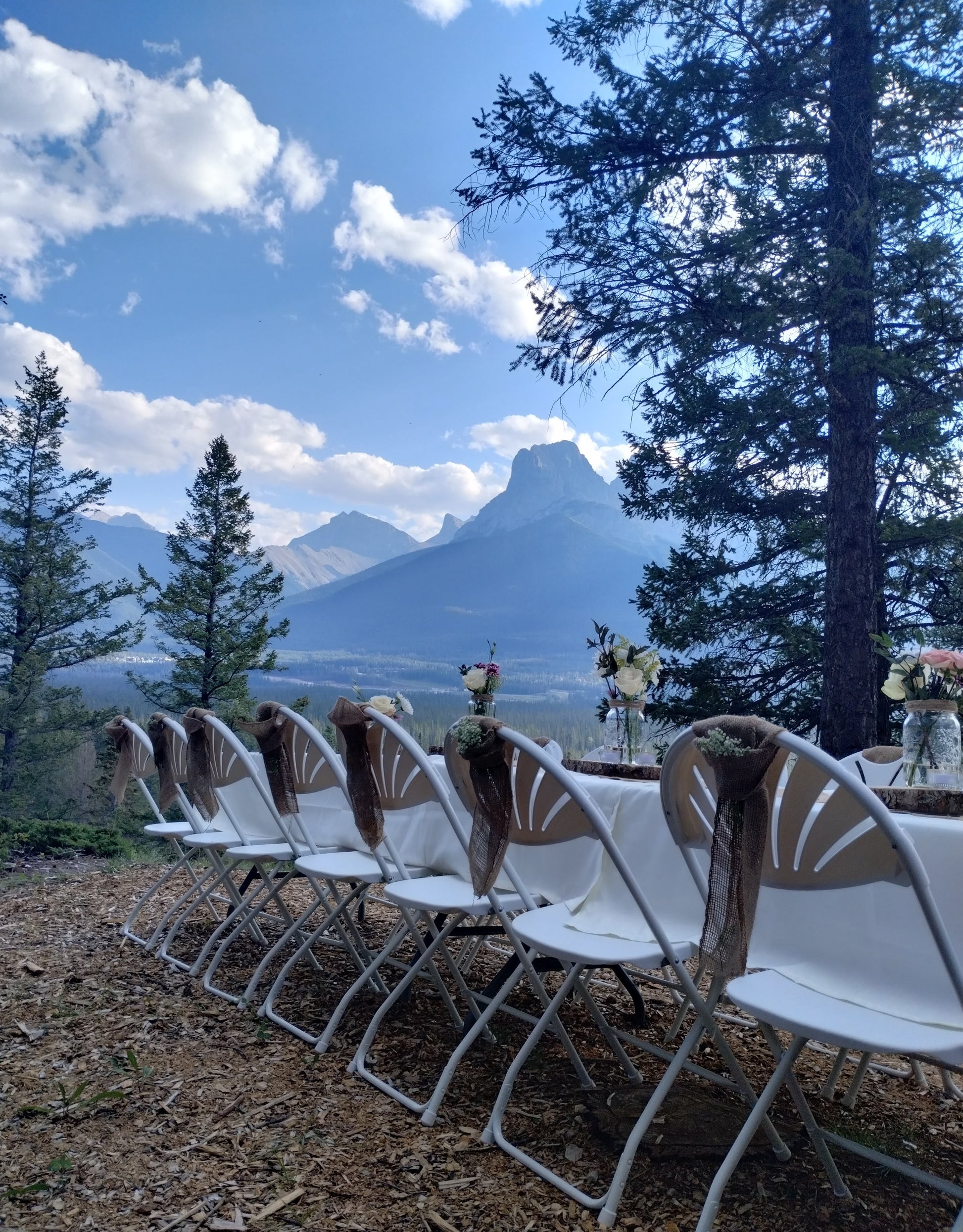 Snow white, fan back, folding chair. View with mountain backdrop.